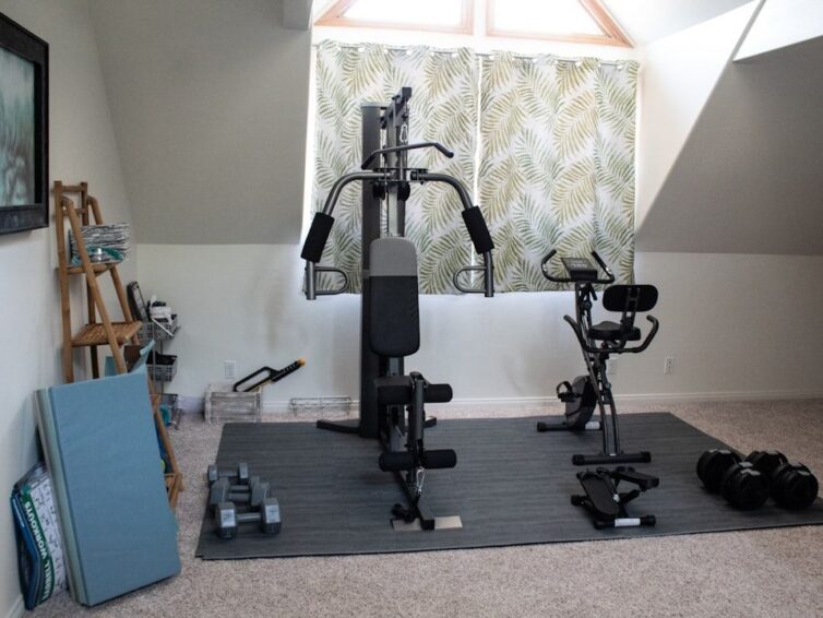 Ett välutrustat hemmagym med en multigym-maskin, motionscykel och hantlar.