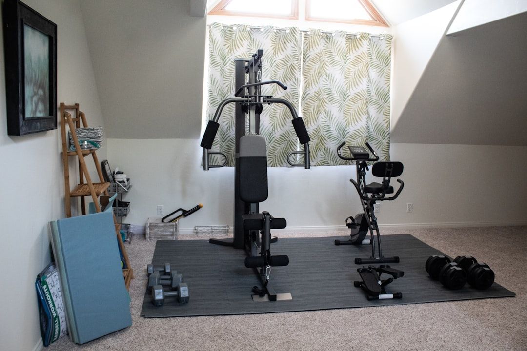 Ett välutrustat hemmagym med en multigym-maskin, motionscykel och hantlar.