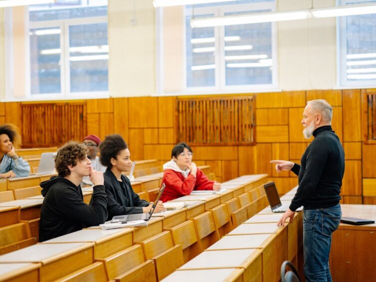 Lärare diskuterar med studenter i en universitetsföreläsningssal